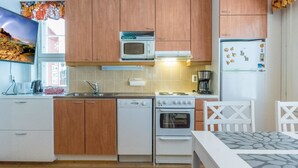 A compact kitchen with wooden cabinets, a microwave, a stove, and a refrigerator.