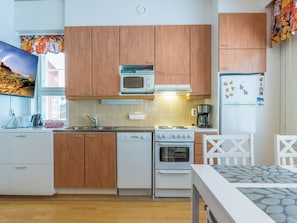 Una cocina con armarios de madera, microondas, estufa y refrigerador.