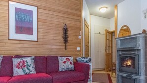A cozy living room with a red sofa, a fireplace, and a wooden wall.