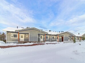 A row of single-story homes with a snow-covered ground, a clear sky, and a white picket fence. - Apartment helmi saariselkä by Interhome (Inari)