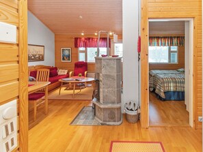 A cozy room with a stone fireplace, wooden furniture, and a bed with plaid bedding.