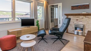 Ein modernes Wohnzimmer mit Kamin, Fernseher und einer gemütlichen Sitzecke.
