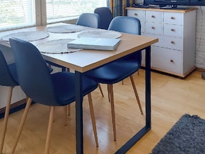 Et spiseområde med et bord, stole og et hvidt skab.