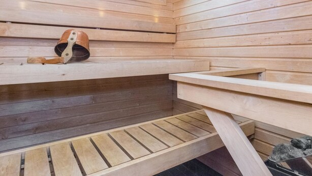 Una sauna con bancos de madera y una banca con una toalla.