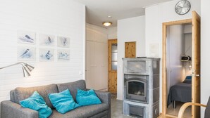Una sala moderna con un sofá gris, cojines turquesa, una chimenea y pinturas de pájaros colgadas en la pared.