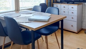 Un comedor con una mesa de madera, sillas azules y un armario blanco con cajones.