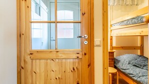 A wooden door with a window, a bunk bed, and a small table.