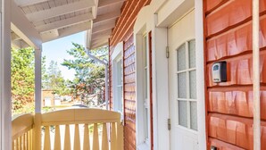 A wooden house with a porch, a door, and a mailbox.