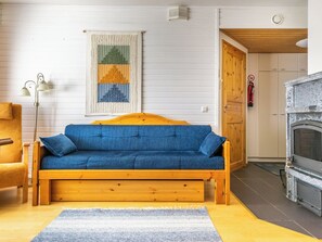 Una habitación acogedora con un sofá de madera, una alfombra pequeña, una lámpara de pared y una chimenea.