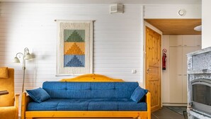 A cozy living room with a blue sofa, wooden floor, and a fireplace.