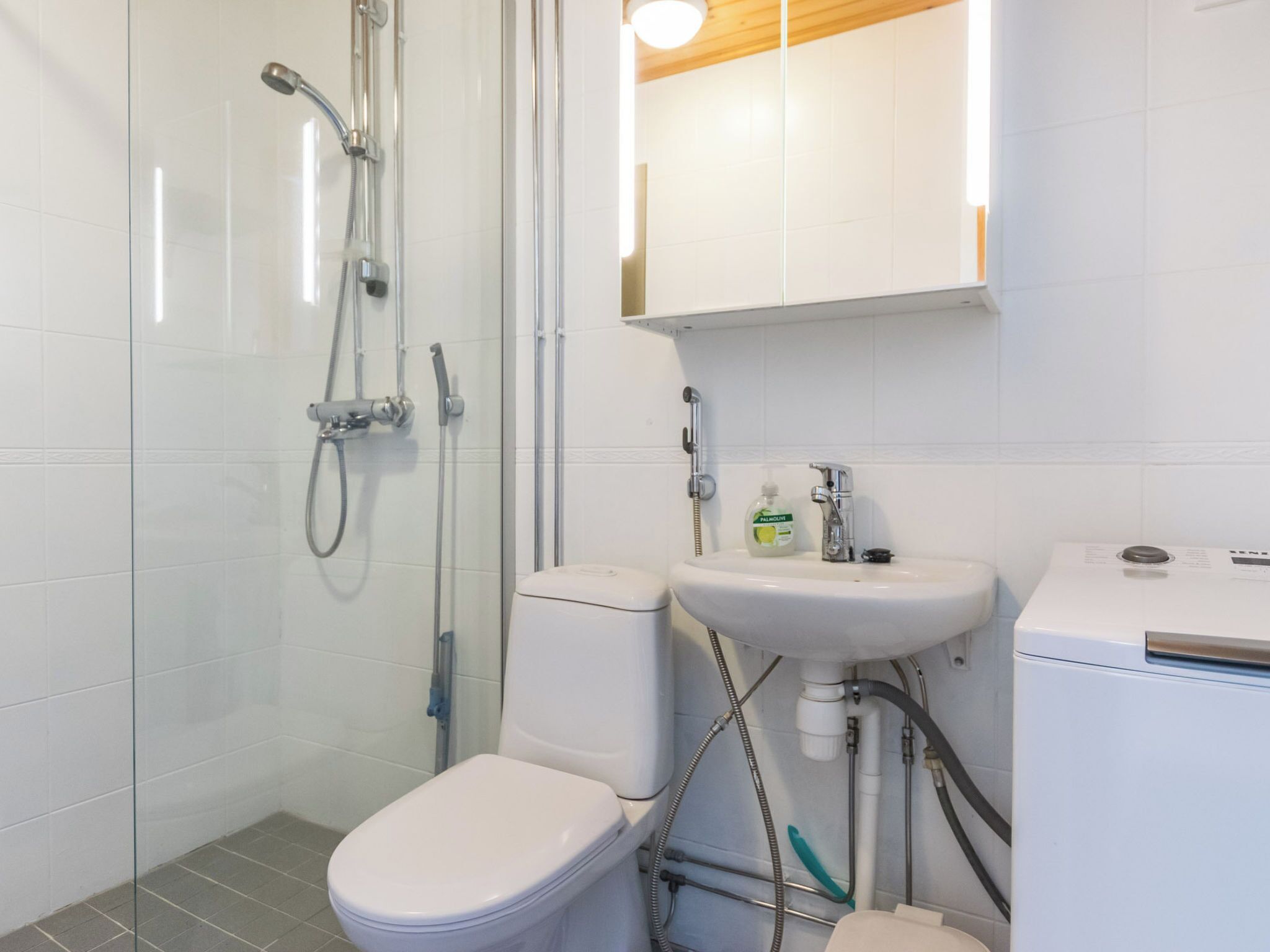 Une salle de bain équipée d’une douche, de toilettes, d’un lavabo et d’un lave-linge.