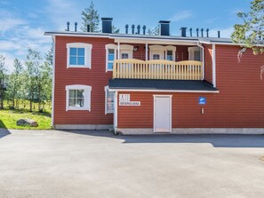 En rød bygning med balkon, dør og et skilt med teksten 'OUTPAILAKKA'.