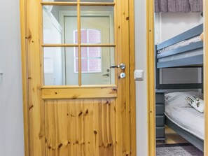 A wooden door with a window, a bunk bed, and a light switch.