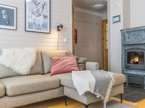 En hyggelig stue med sofa, pejs og billeder i rammer på væggen.