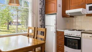 Een keuken met houten kastjes, een koelkast, een magnetron en een fornuis.