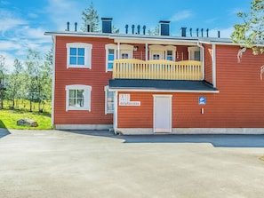 Een rood gebouw met een balkon en een deur waarop 'OUTPAILAKKA' staat.