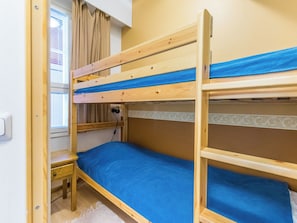 Un lit superposé avec une structure en bois et une literie bleue.