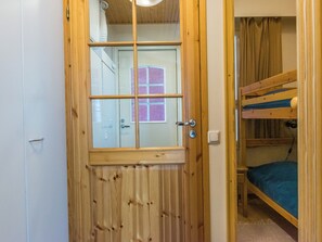 Una puerta de madera con un ventanal, una cama litera e interruptor de luz.