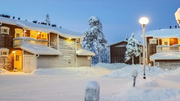 Un quartier résidentiel enneigé, avec des maisons, un lampadaire et une boîte aux lettres.