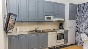 Une cuisine de taille réduite avec des meubles gris, un four à micro-ondes, une cuisinière et un réfrigérateur.