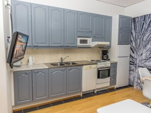 Une cuisine compacte avec des meubles gris, un four à micro-ondes, une cuisinière et une machine à café.