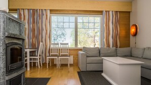 Een woonkamer met een open haard, een bank, een salontafel en een eethoek met stoelen.