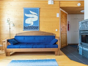 Ein Zimmer mit Holzboden, einem blauen Sofa, einer Wandteppich, einer Lampe und einem Kamin.