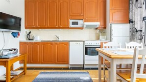 A compact kitchen with wooden cabinets, a microwave, a stove, and a dishwasher. - Outapailakka j 9 by Interhome (Inari)