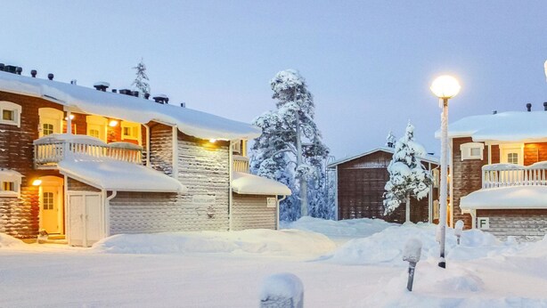 A snow-covered building with a stone facade, a wooden door, and a balcony. - Outapailakka j 9 by Interhome (Inari)