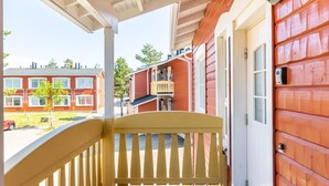 A wooden porch with a yellow railing, a door with a mailbox, and a view of neighboring buildings. - Outapailakka j 9 by Interhome (Inari)