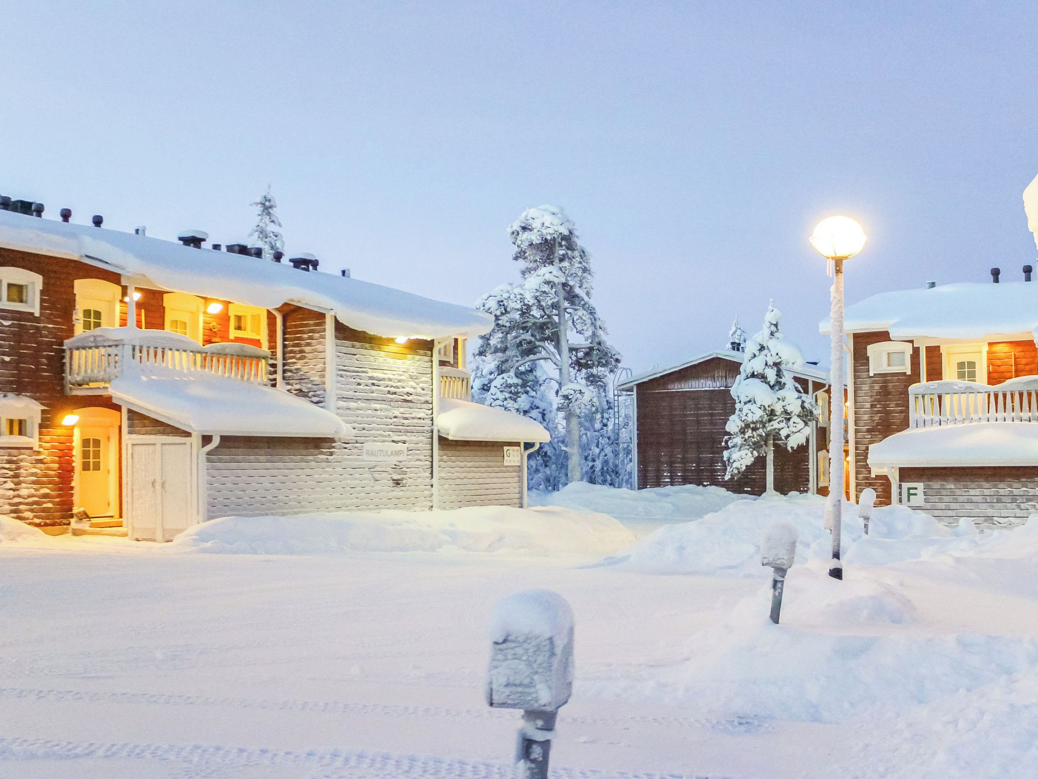Et snæverkket boligområde med huse, en lygtepæl og en postkasse.