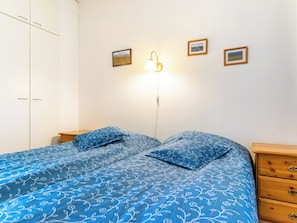 Une chambre à coucher comprenant un lit, deux tables de chevet, une armoire et une lampe fixée au mur.