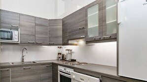 Een moderne keuken met grijze kastjes, een ingebouwde magnetron, een spoelbak, een kookplaat en een vaatwasser.