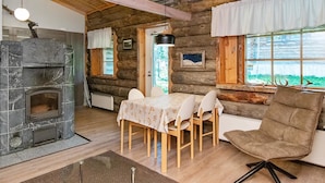 Een knus blokhutinterieur met een stenen open haard, een houten eettafel en stoelen.