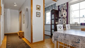 Ein Essbereich mit Tisch für vier Personen, Holzboden, einem gemusterten Teppich und einem Fenster mit Vorhängen.