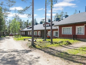 A row of cabins with a dirt path leading to them, surrounded by trees.