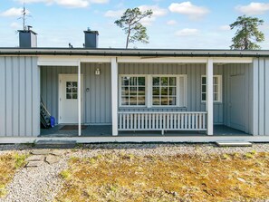 En etagers bygning med en overdækket veranda, en dør og et vindue.