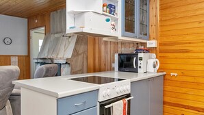 Eine kompakte Küche mit Mikrowelle, Backofen und einem kleinen Schrank über der Arbeitsplatte.