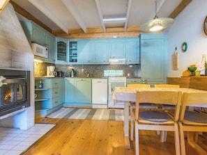 Une cuisine avec des meubles de couleur turquoise, une table à manger en bois et un plan de travail en pierre.