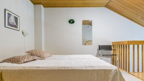 Un dormitorio con cama, almohadas, un reloj, un espejo y una barandilla de madera.