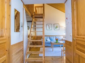 Een houten interieur met een trap, een bank en een bijzettafeltje.