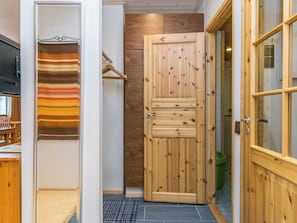 A wooden wardrobe with a sliding door, a hanging rack, and a tiled floor.
