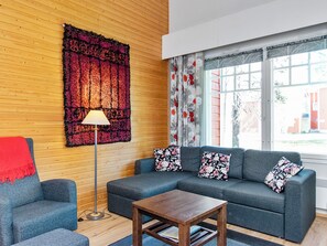 A modern living room with a sectional sofa, a small table, a floor lamp, and a large floral tapestry on the wall.