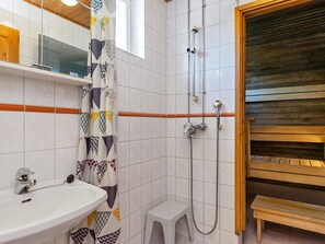 Bathroom features a shower with handheld showerhead and wall-mounted faucet, a sink with chrome faucet, and a mirror.