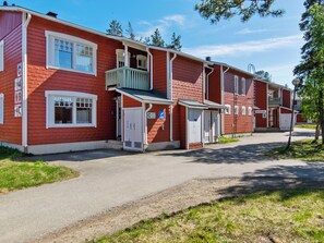 A row of red wooden buildings with white trim, a covered walkway, and a clear sky.