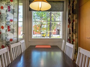 A dining area with a large window, white chairs, and a table.