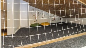 Een kamer met een schuine kap, een houten vloer en een speelgedeelte met net.