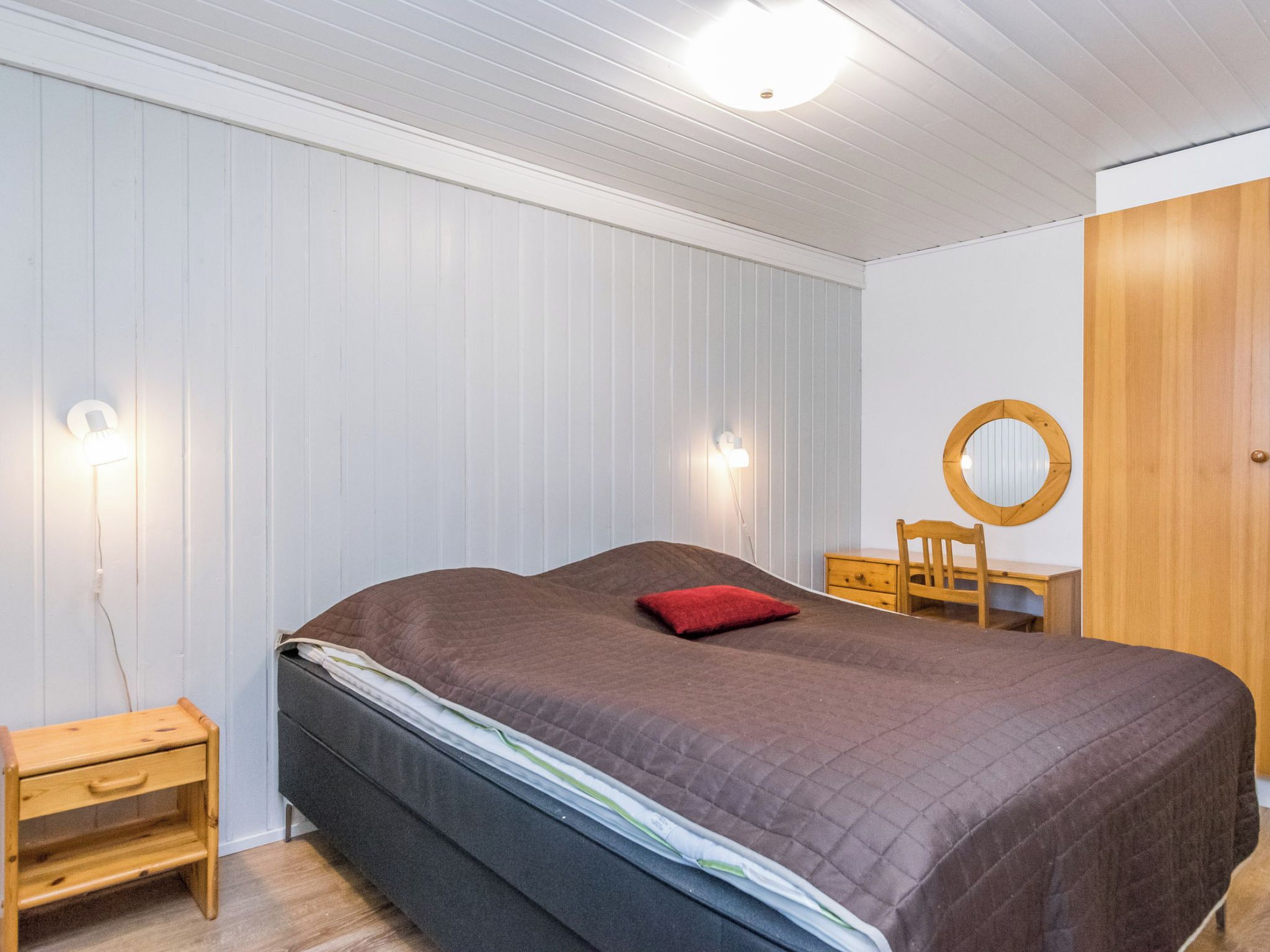 Ein Schlafzimmer mit einem Bett, einem Nachttisch, einer Kommode und einem Spiegel.