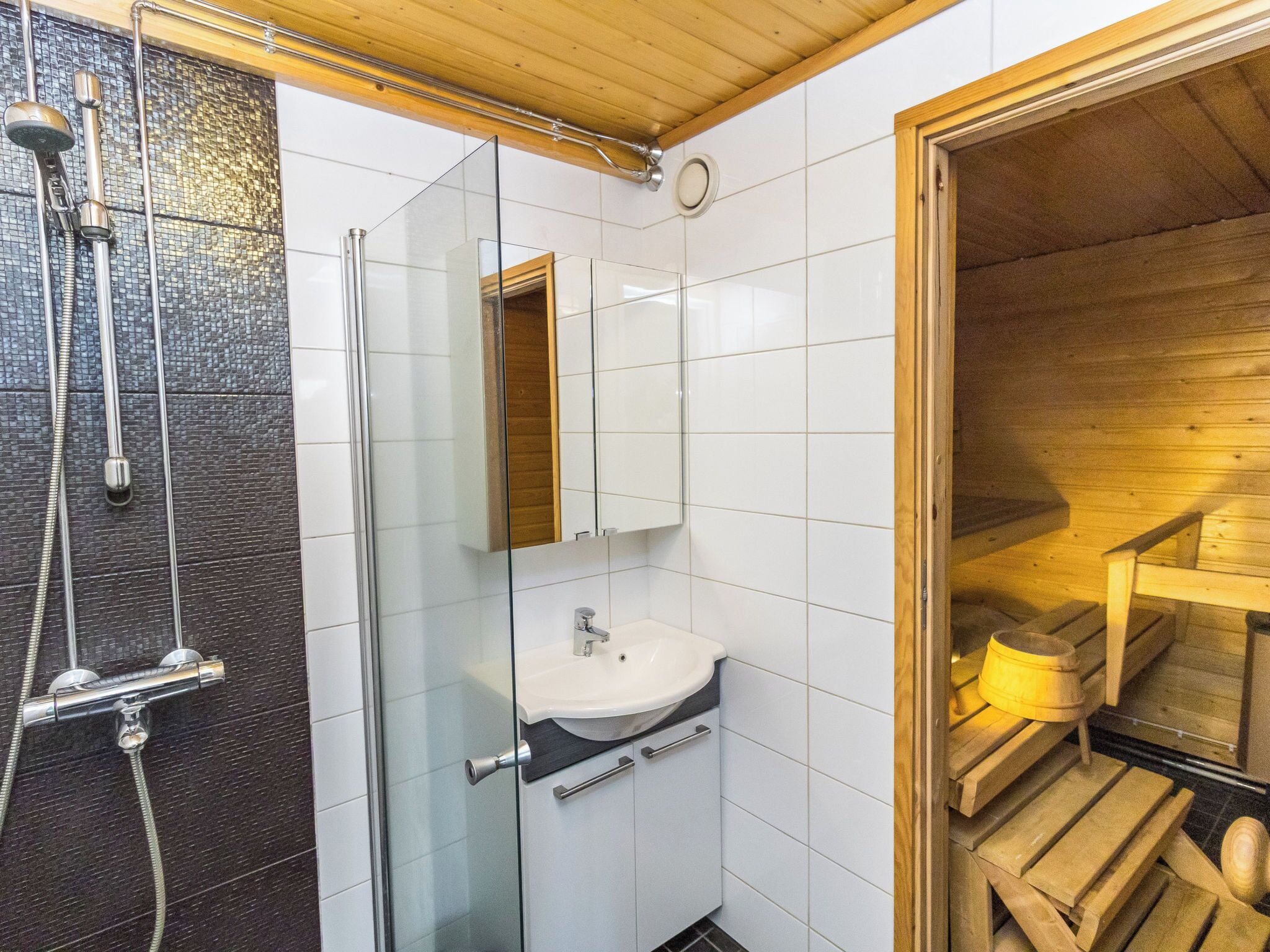 Un baño moderno con cabina de ducha de vidrio, lavamanos blanco y detalles de madera.