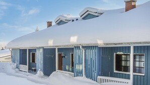Een gebouw bedekt met sneeuw, met een blauwe gevel en meerdere schoorstenen.